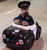 A stuffed animal dog driving a cop car