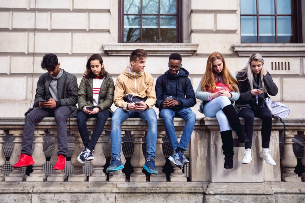 A group of teens looking down at their cell phones